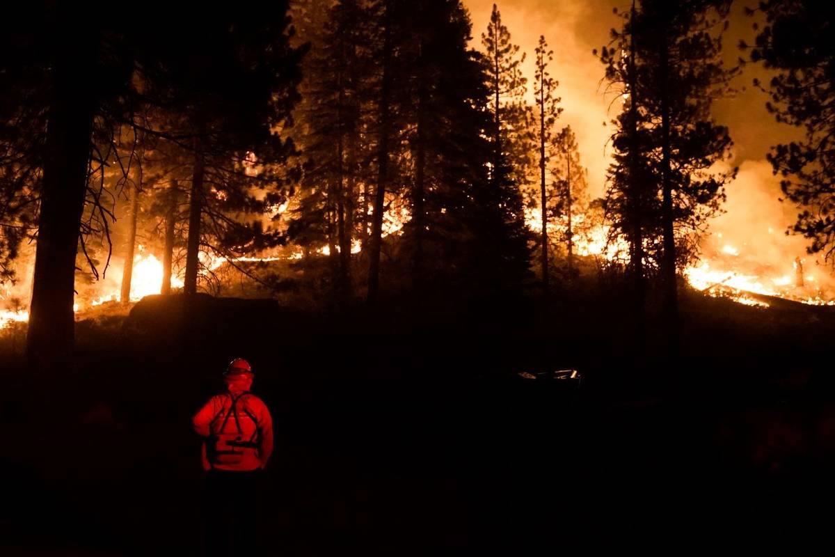A firefighter monitors the Caldor Fire burning near structures in South Lake Tahoe, Calif., Mon ...
