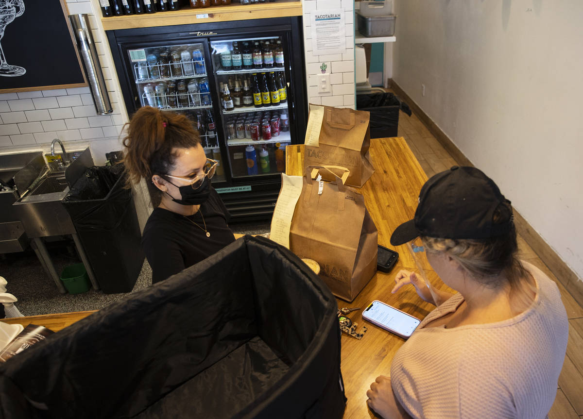 Sandra Ruiz, left, Tacotarian manager, checks out customers order as Michelle English, a delive ...