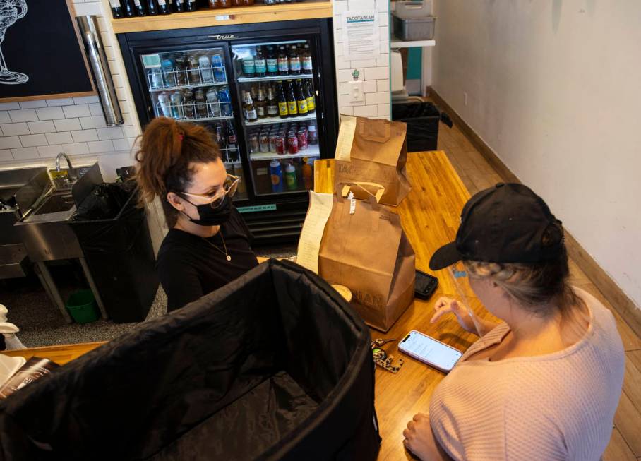 Sandra Ruiz, left, Tacotarian manager, checks out customers order as Michelle English, a delive ...