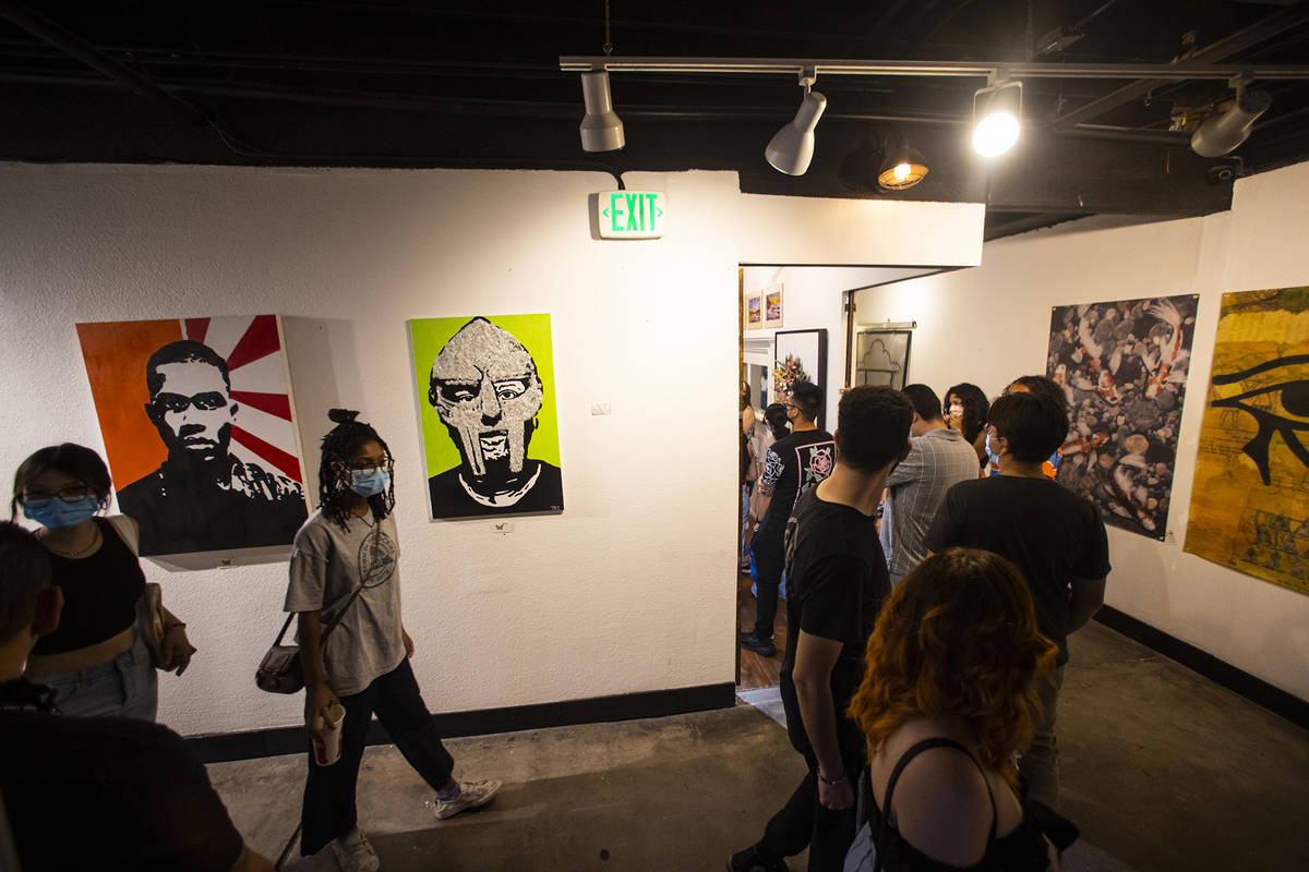People walk past a portrait of the late rapper MF DOOM by artist Taylor Rene Williams at the Ar ...