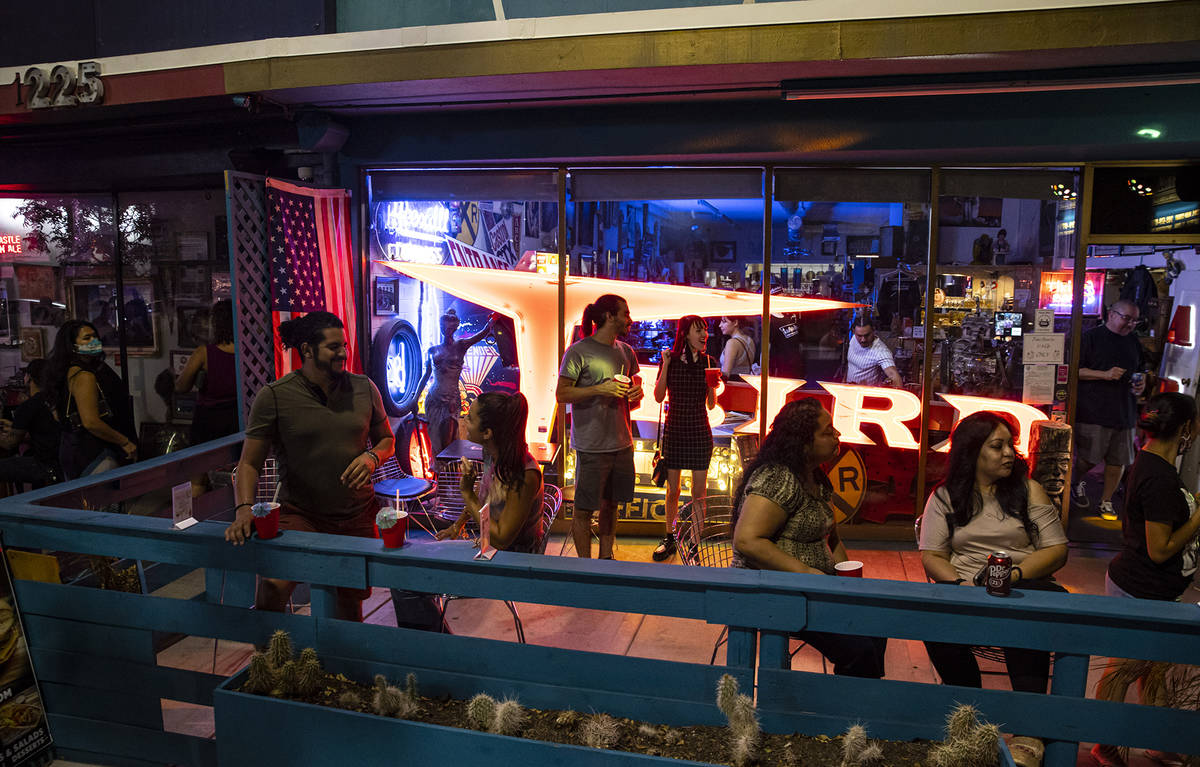People enjoy drinks and music from a DJ at Vintage Vegas Antiques during First Friday in the Ar ...