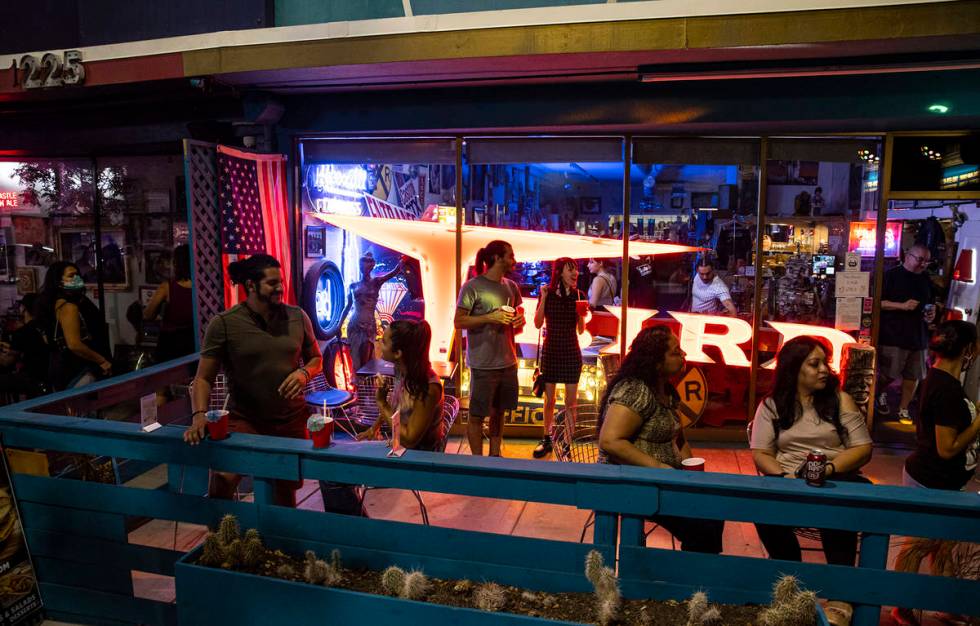 People enjoy drinks and music from a DJ at Vintage Vegas Antiques during First Friday in the Ar ...