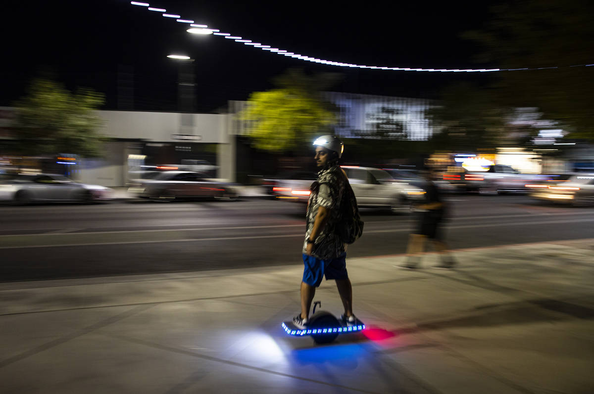 A man passes by on a Onewheel electric skateboard on Main Street during First Friday in the Art ...
