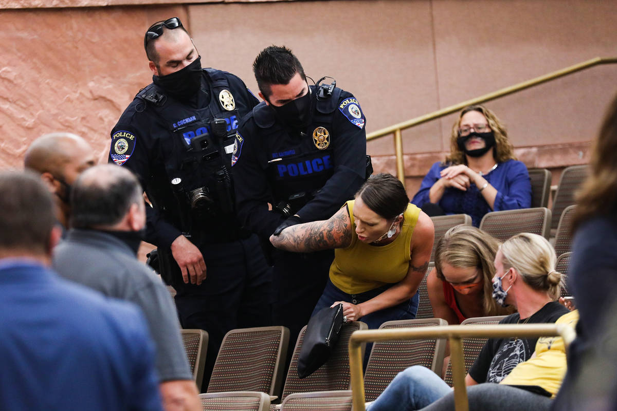 A woman is escorted out by police after disrupting a Clark County School Board meeting regardin ...