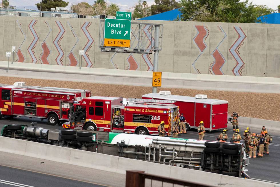 Emergency personnel work at the scene where a fuel tanker truck overturned on U.S. Highway 95 o ...