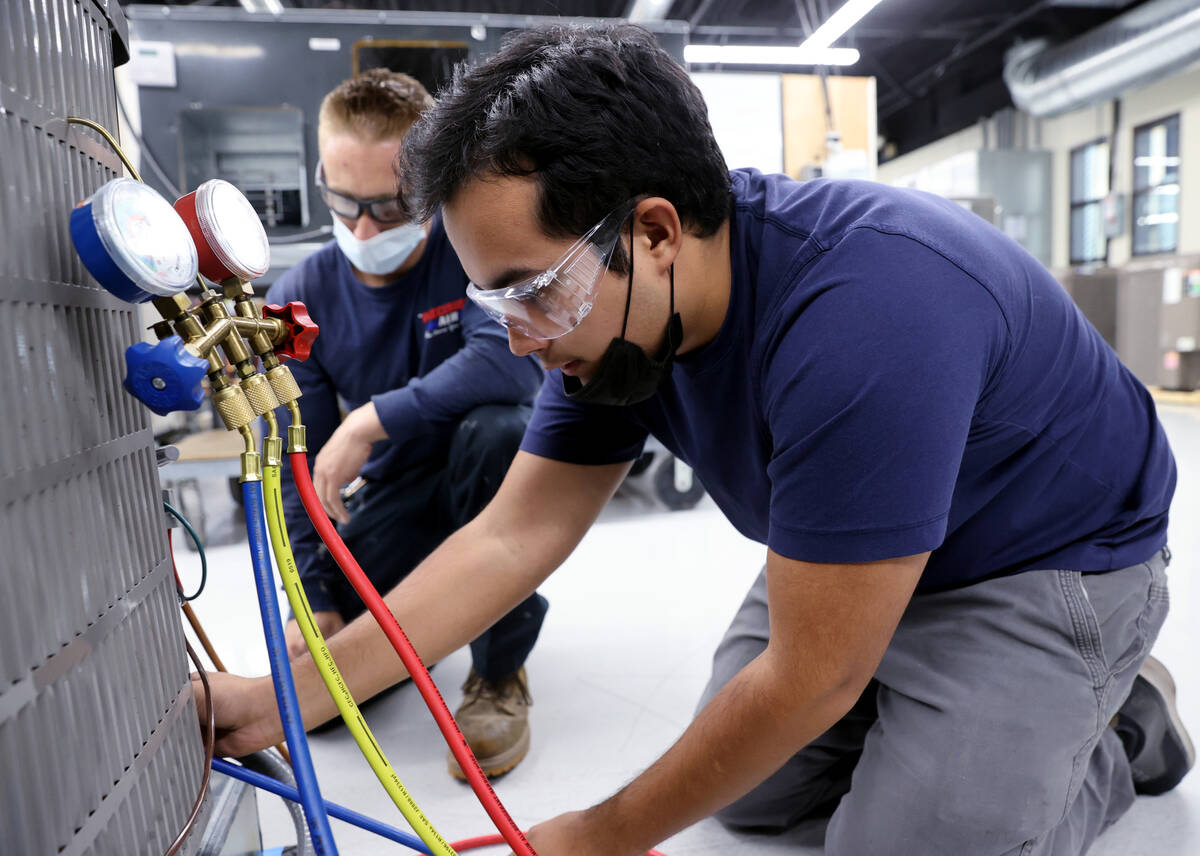 Students Rene Morales, right, and Anthony Viola work on an air conditioning unit during an HVAC ...
