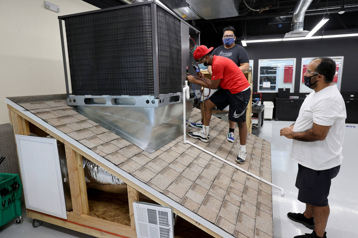 Students, from left, Brandon Dickerson, Kevin Navarro and Eric Ramos work on a rooftop air cond ...