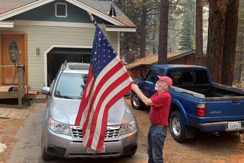 Bill Roberts rolls up an American flag in front of his house in South Lake Tahoe, Calif., on Tu ...