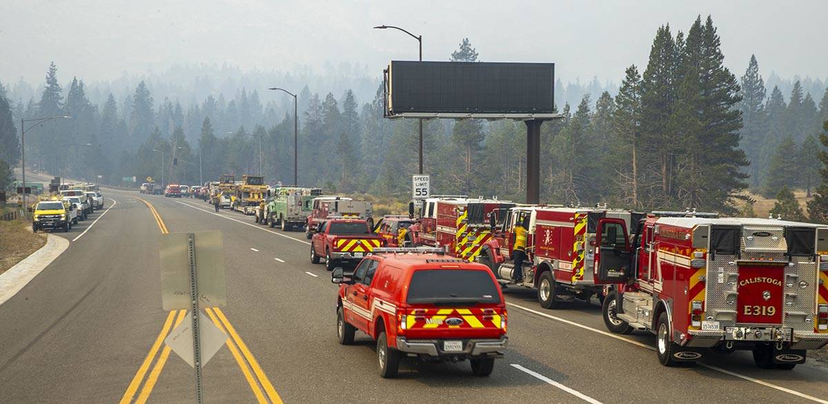 Dozens of emergency vehicles are staged as smoke fills the sky with the Caldor Fire on the move ...