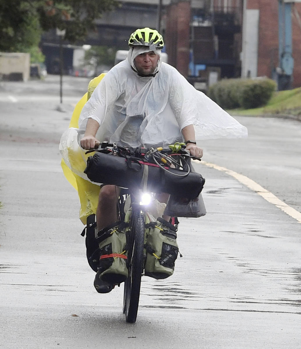 With the rain falling, a bicyclist dressed in wet weather gear travels along the Great Alleghen ...