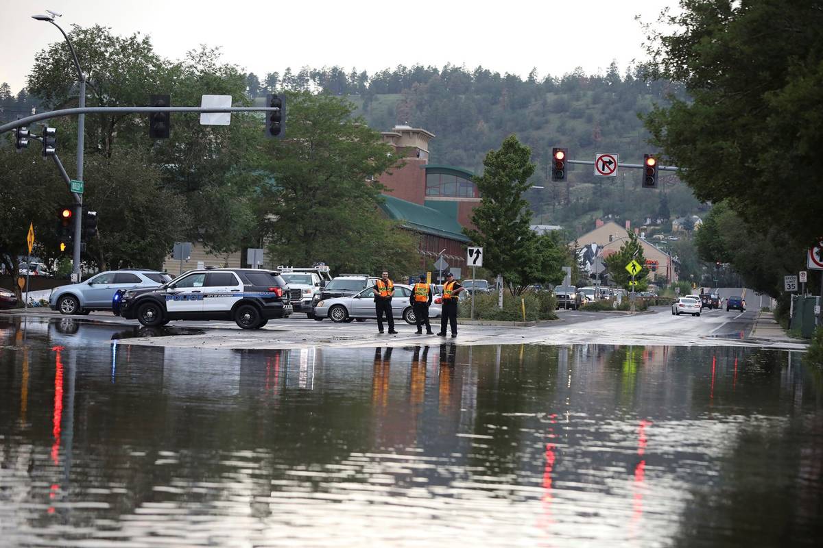 Flagstaff police officers stand at the edge of street flooding, Tuesday, Aug. 17, 2021, in Flag ...