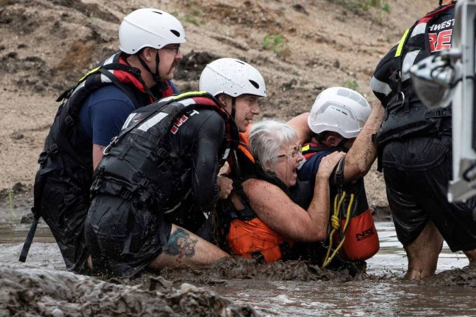 A team of Northwest Fire District firefighters walk a woman away from a stranded pickup truck i ...