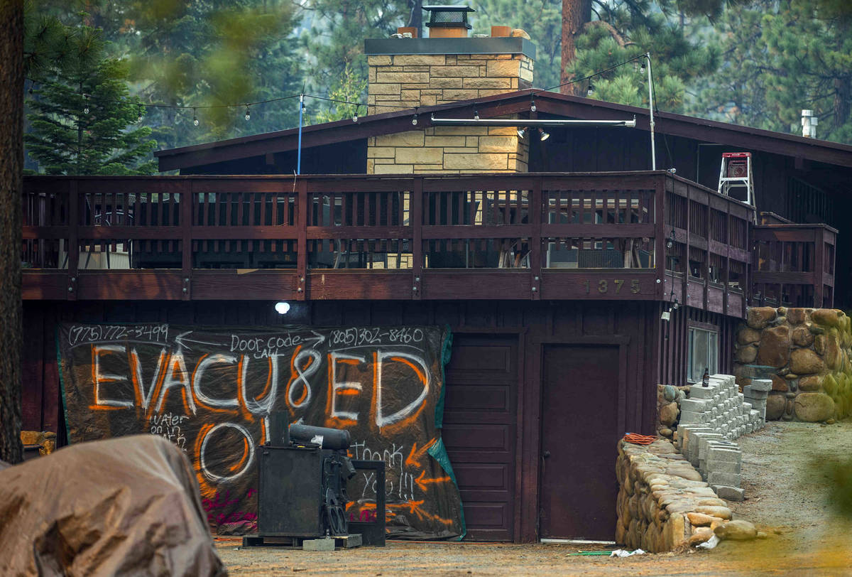 A sign is hung on the garage of an evacuated home from the Caldor Fire in Tahoe Meadows on Wedn ...