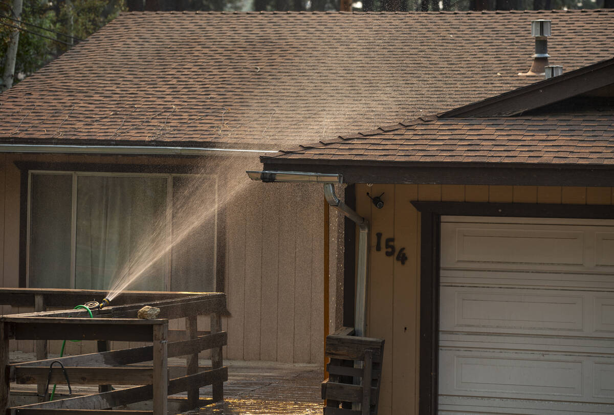 A sprinkler douses of evacuated home from the Caldor Fire on Wednesday, Sept. 1, 2021, in Kings ...