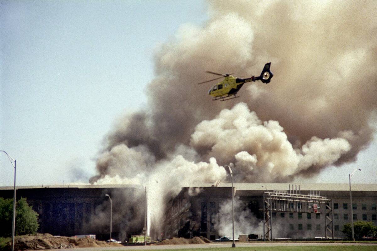 FILE - A helicopter flies over the Pentagon in Washington as smoke billows over the building on ...
