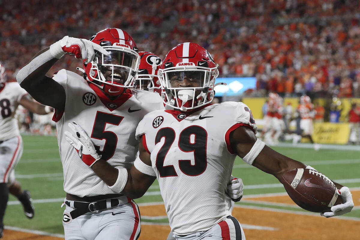 Georgia defensive back Christopher Smith celebrates with Kelee Ringo, left, after intercepting ...