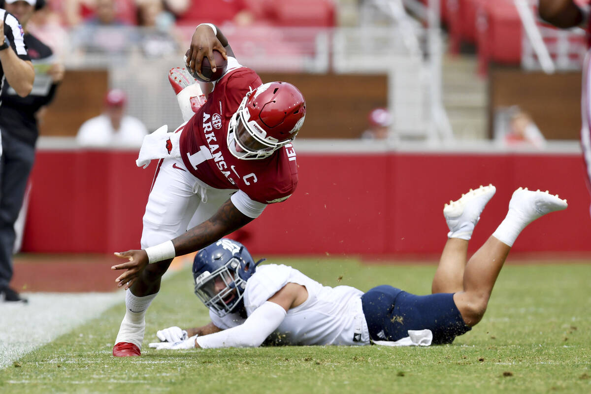 Arkansas quarterback KJ Jefferson (1) is tripped up by Rice defender Cameron Montgomery (1) as ...