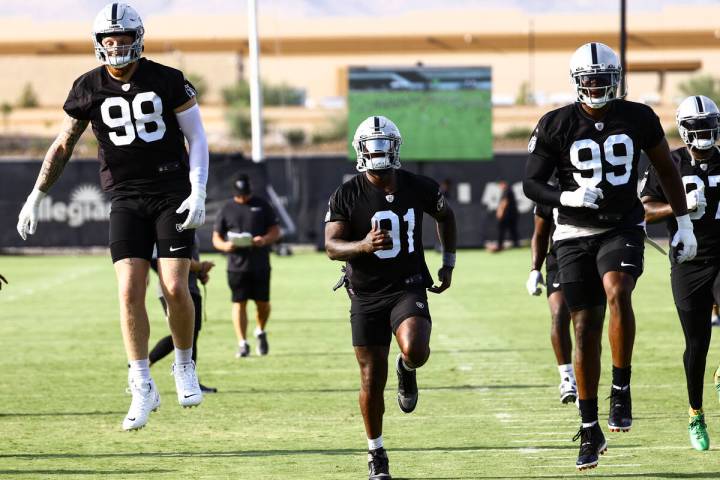 Raiders defensive ends Maxx Crosby (98), Yannick Ngakoue (91) and Clelin Ferrell (99) warm up d ...