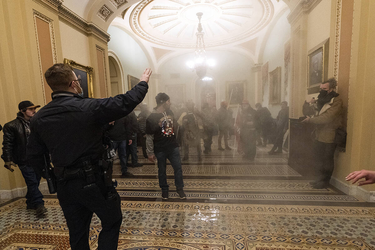 FILE - In this Jan. 6, 2021, file photo, smoke fills the walkway outside the Senate Chamber as ...