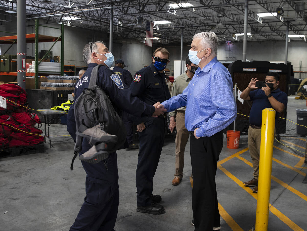 Gov. Steve Sisolak shakes hands with a members of the Nevada Task Force 1, Michael Porter, afte ...