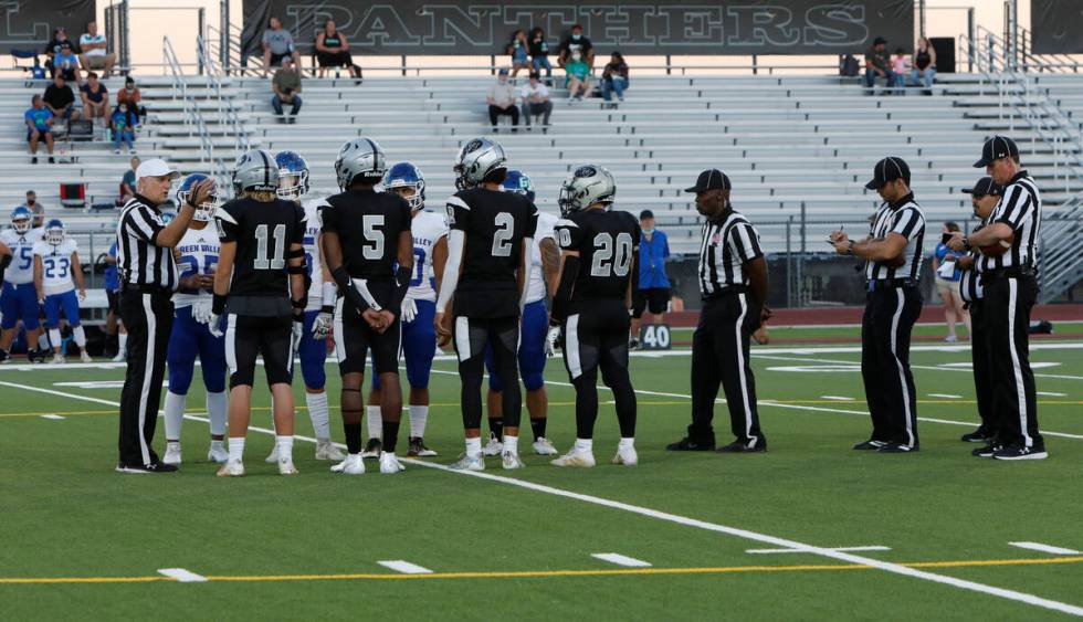 Referee Shane Lewis, left, white cap, talks to players during the coin toss before a football g ...