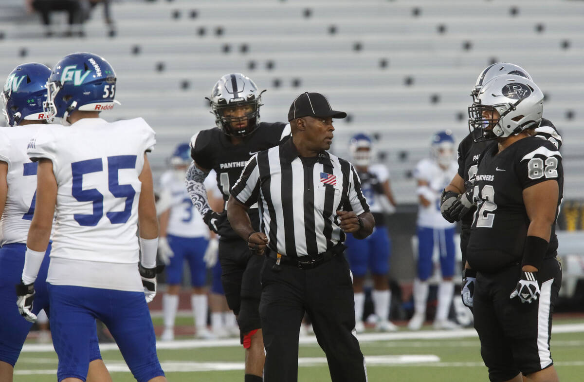 Umpire Gordon Washington, center, talks to players during the first half of a football game bet ...