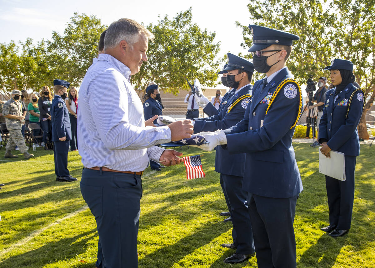 Scott Edwards, left, receives a ceremonial flag from Air Force JROTC cadet Gavin Birch along wi ...