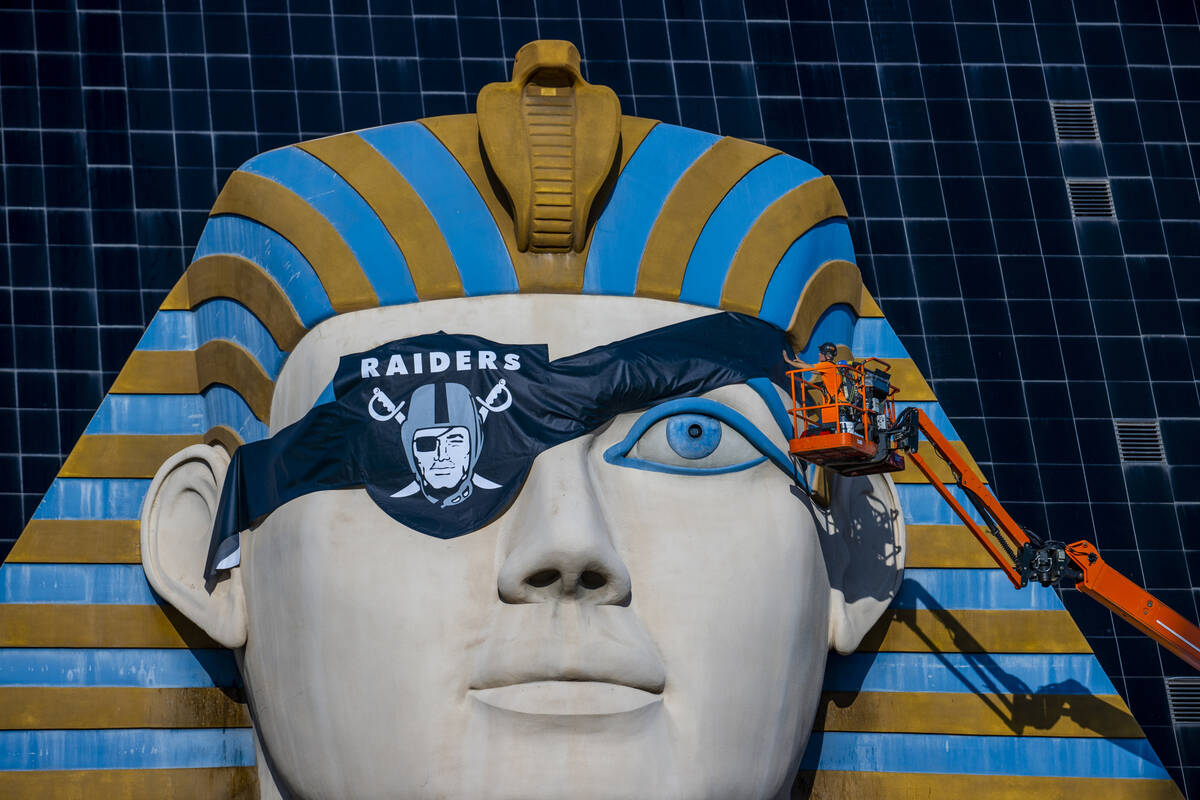 Billy Baker, left, and Miguel Lopez with Access Solutions hang a Raiders eye patch on the Great ...