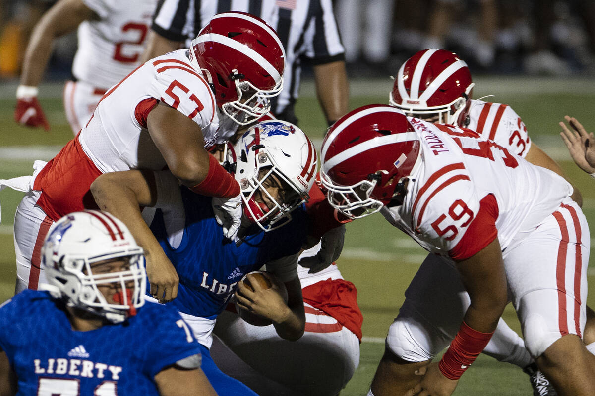 Liberty quarterback Jayden Maiava (1) sacked by Mater Dei defensive end Michael Alvarez (57) an ...