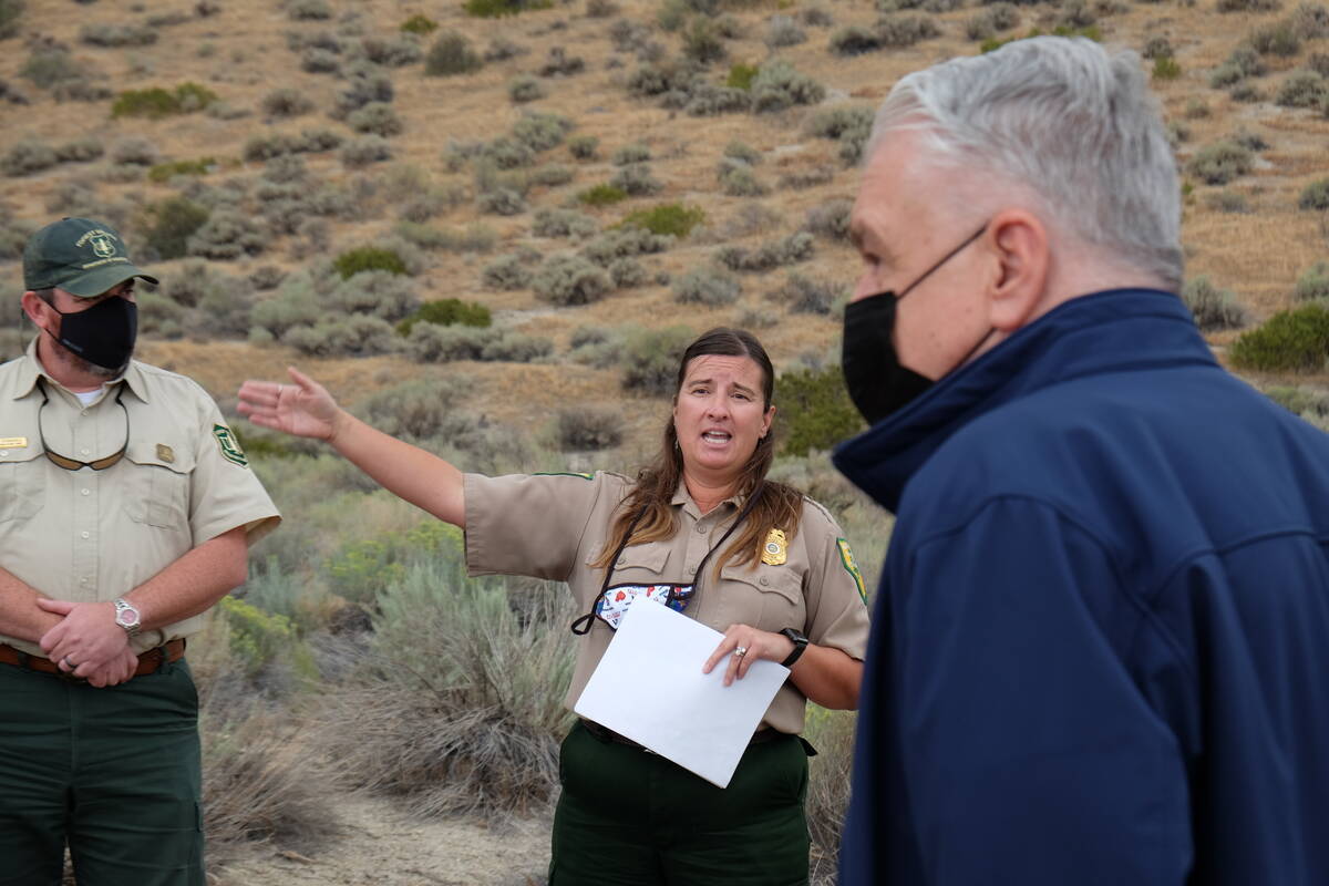 State Forester Kacey KC briefs the governor and others on work done to clear vegetation around ...