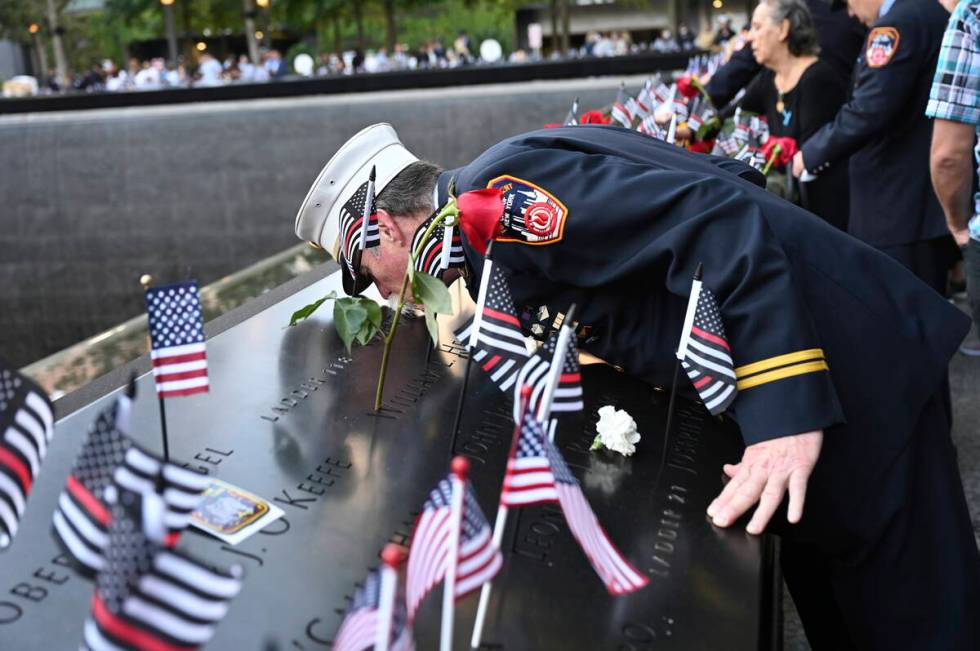 Retired Paramedic Chief Charlie Wells kisses the name of a relative killed in the attack on the ...