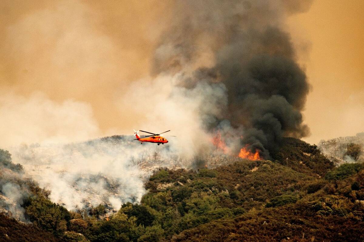 A helicopter prepares to drop water on the KNP Complex Fire in Sequoia National Park, Calif., o ...