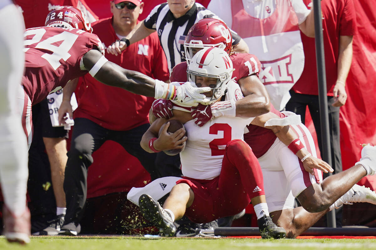 Nebraska quarterback Adrian Martinez (2) is brought down by Oklahoma linebackers Nik Bonitto (1 ...