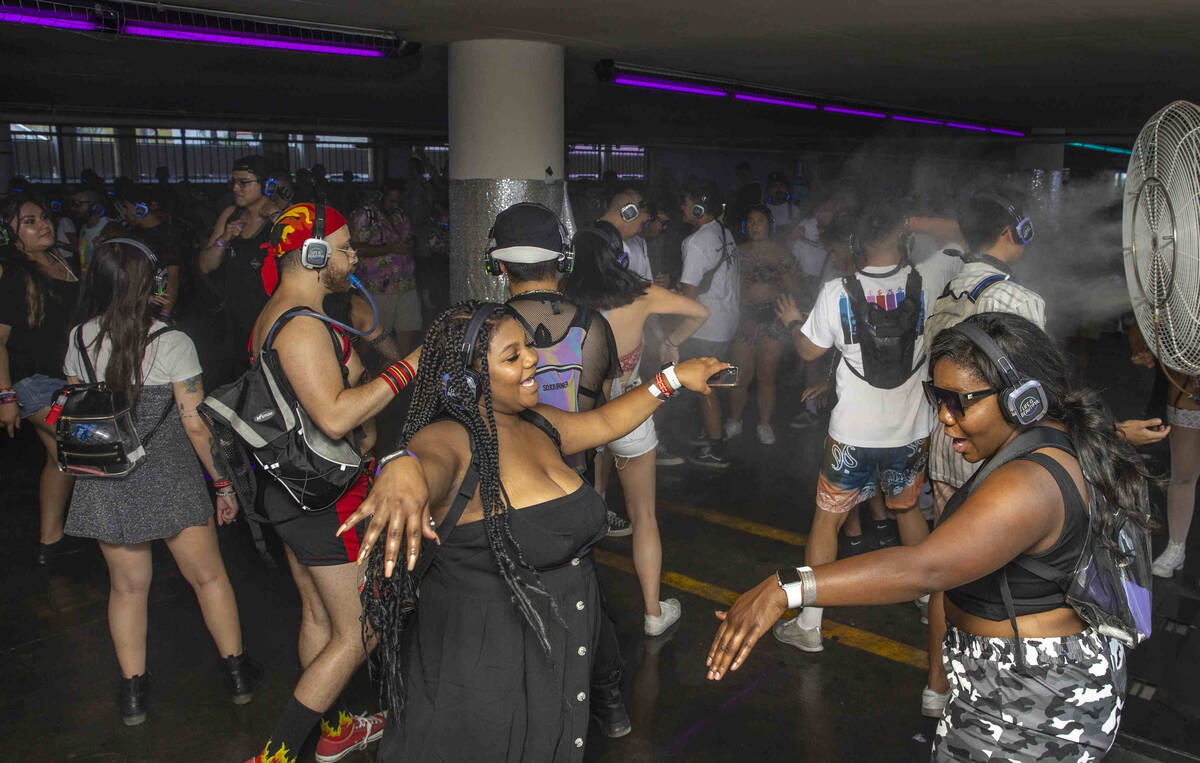 People dance within a silent disco in a parking lot garage off of South 7th Street during day o ...