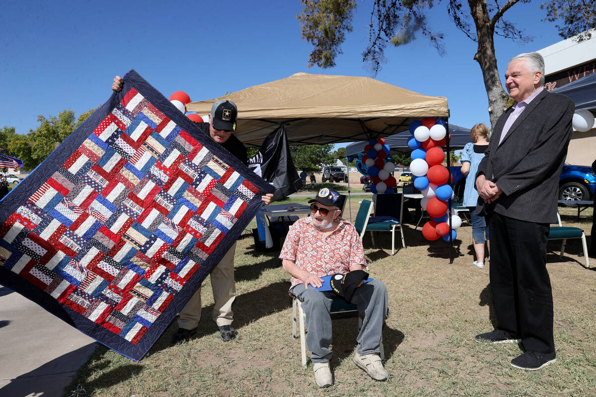 World War II veteran Vincent Shank, center, is gifted a quilt from Patrick Nary, left, as Gov. ...