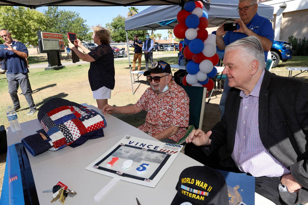 World War II veteran Vincent Shank, left, watches a parade in his honor with Gov. Steve Sisolak ...