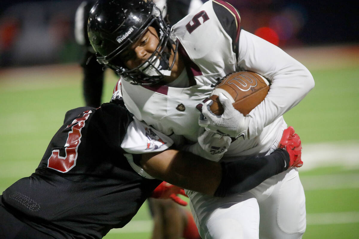 Faith Lutheran High School's Nick Crowell (3) is tackled by Liberty High School's Larry Royal d ...