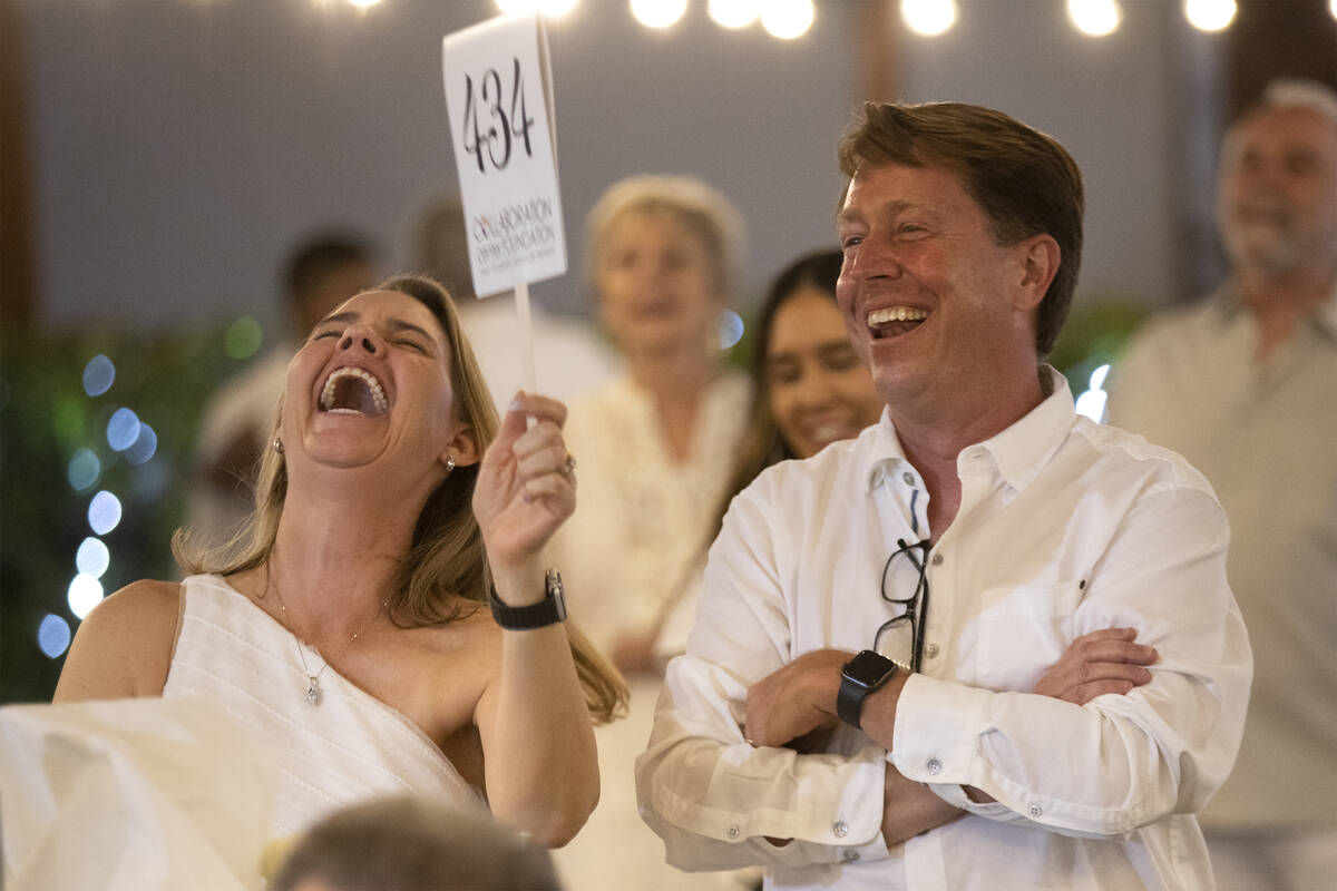 Kathy MacDonald, left, and Kevin MacDonald laugh as they out-bid themselves for a live auction ...