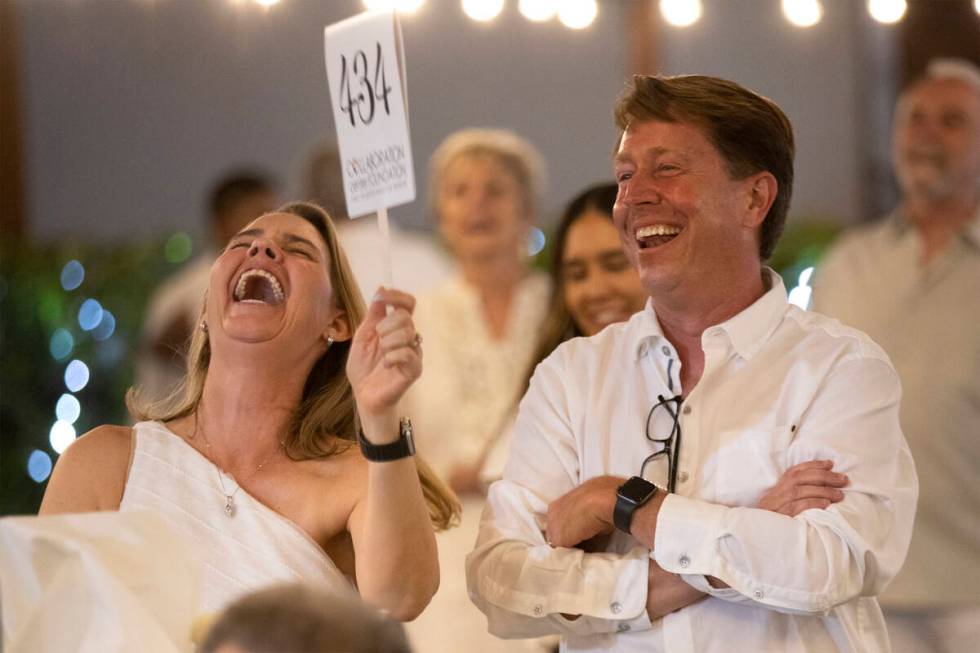Kathy MacDonald, left, and Kevin MacDonald laugh as they out-bid themselves for a live auction ...