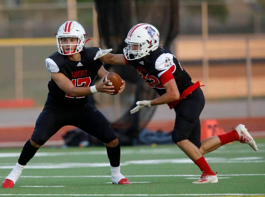 Liberty High School's Colin Gregorio (17) hands off to Liberty High School's Brody Clark (22) d ...