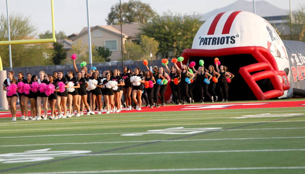 Liberty High School's cheerleaders and dance team members march to the field before a football ...