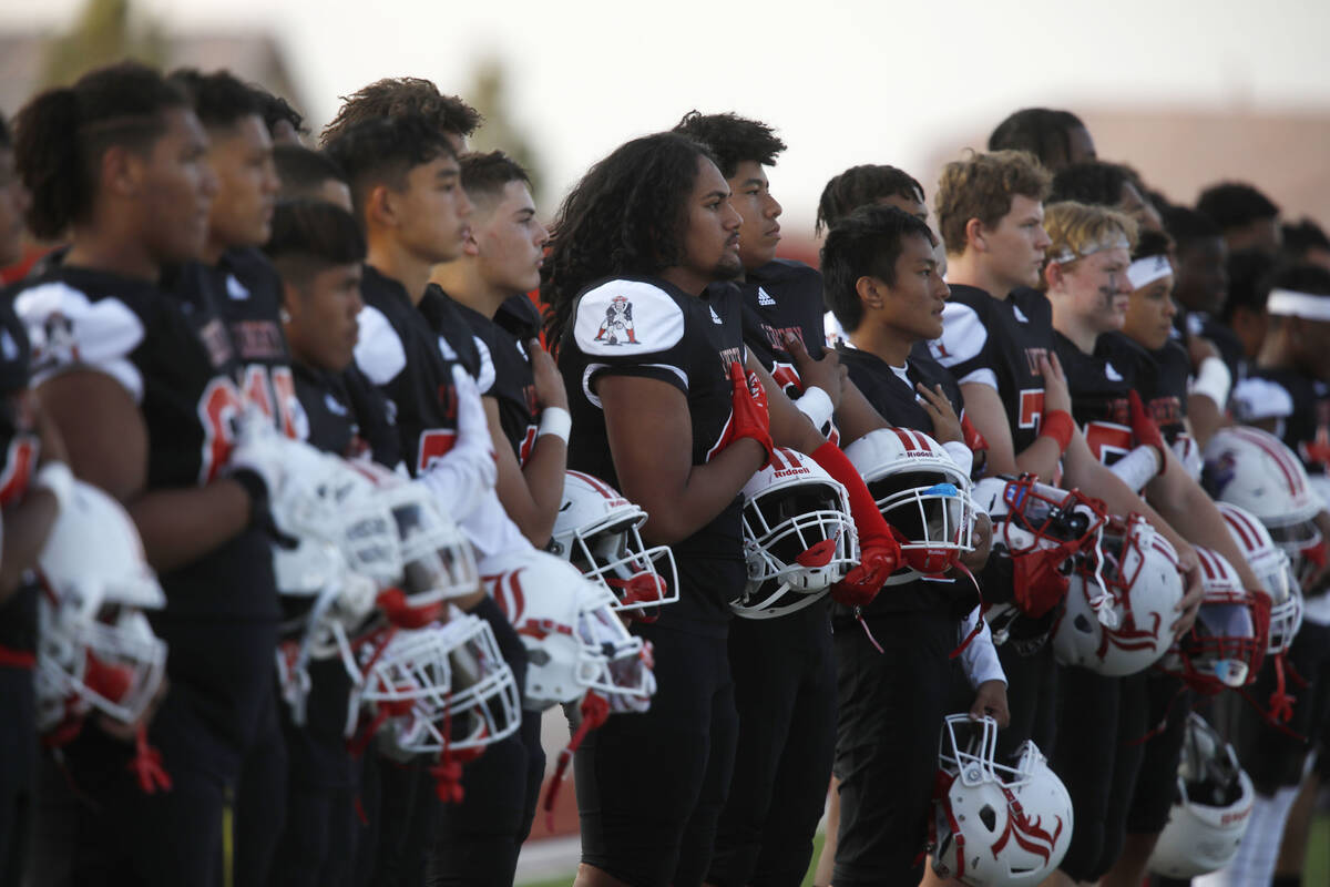 Liberty High School's players stand during the national anthem before a football game against F ...