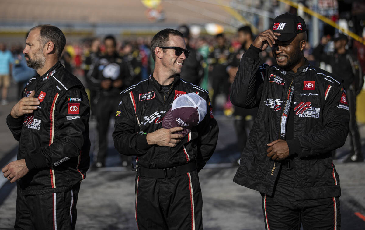 Pit crews listen to the national anthem before the start of the Alsco Uniforms 302 NASCAR Xfini ...