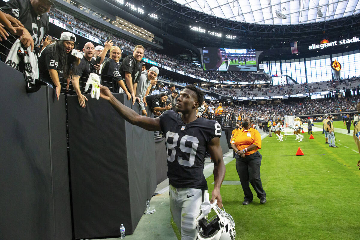 Raiders wide receiver Bryan Edwards (89) hands a glove to a fan while heading off the field aft ...