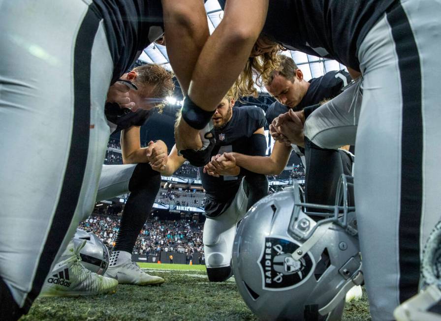Raiders players pray together on the field after defeating the Miami Dolphins 31-28 in the over ...