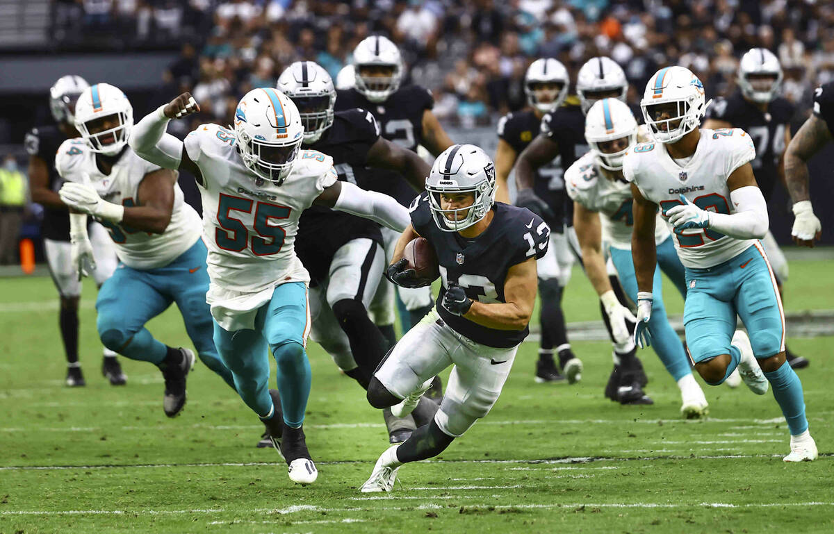 Raiders wide receiver Hunter Renfrow (13) runs the ball under pressure from Miami Dolphins outs ...