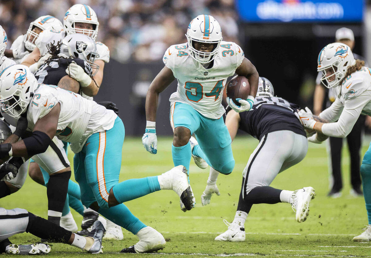 Miami Dolphins running back Malcolm Brown (34) breaks through a hole past Las Vegas Raiders def ...