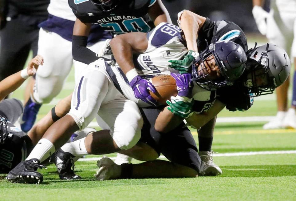 Shadow Ridge High School's Jaquieze Holland (25) is tackled by Silverado High School's Jaden Th ...