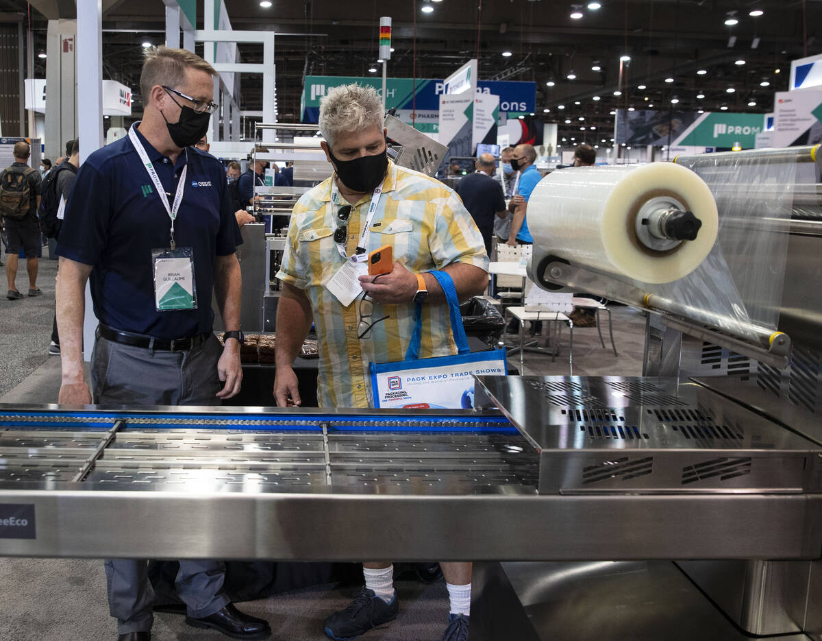 Brian Guillaume, left, of ProMach, talks about ReeEco, an automatic tray sealer, to a potential ...