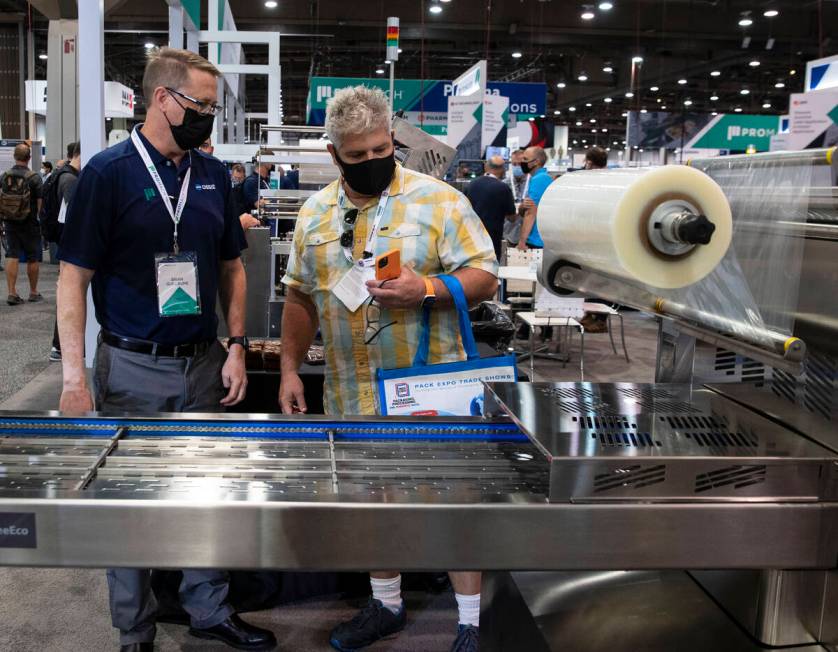 Brian Guillaume, left, of ProMach, talks about ReeEco, an automatic tray sealer, to a potential ...